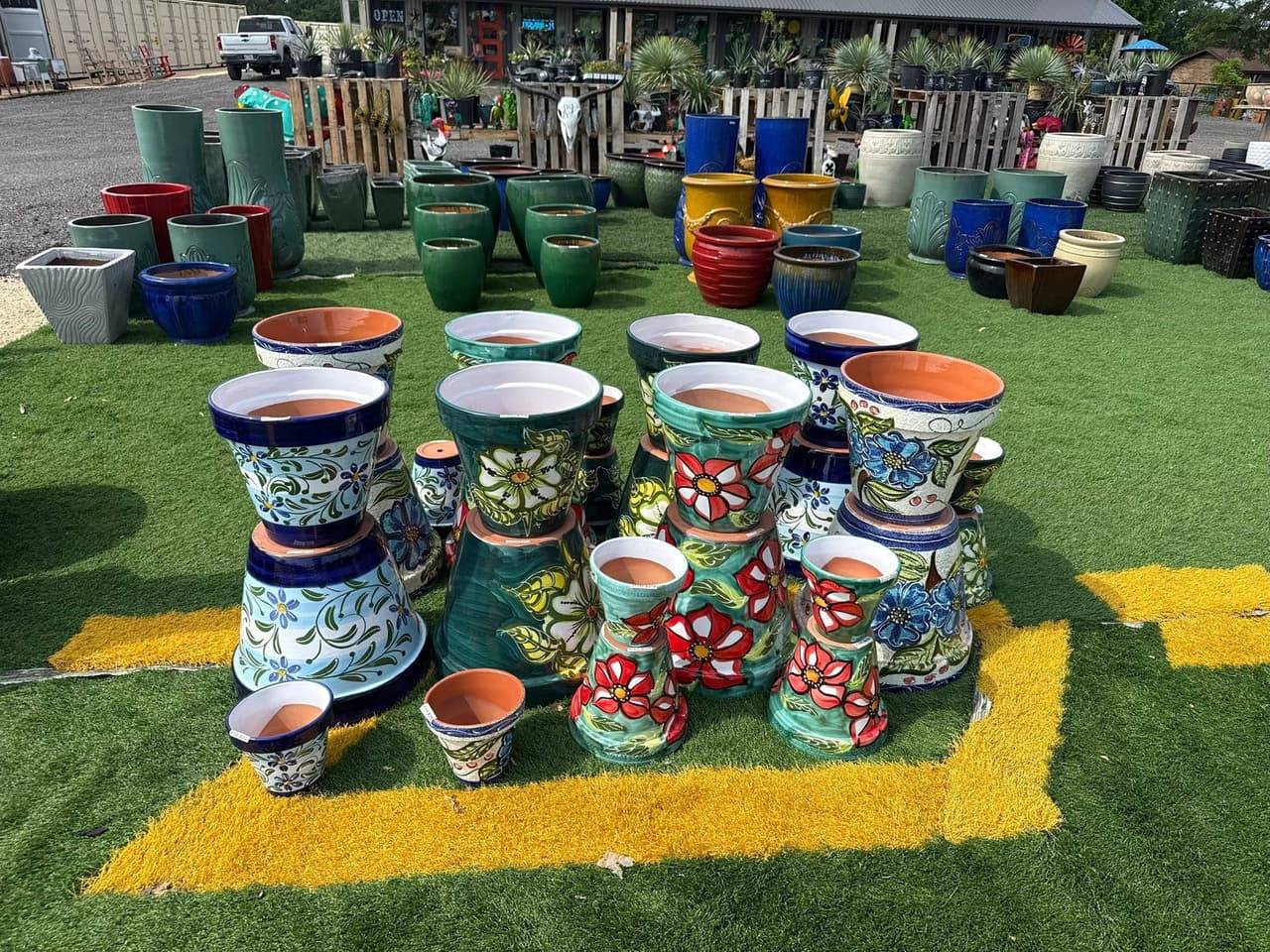 Hand-painted glazed flower pots in blue, teal and red with stacked saucers on the lawn at Pick Ur Pots