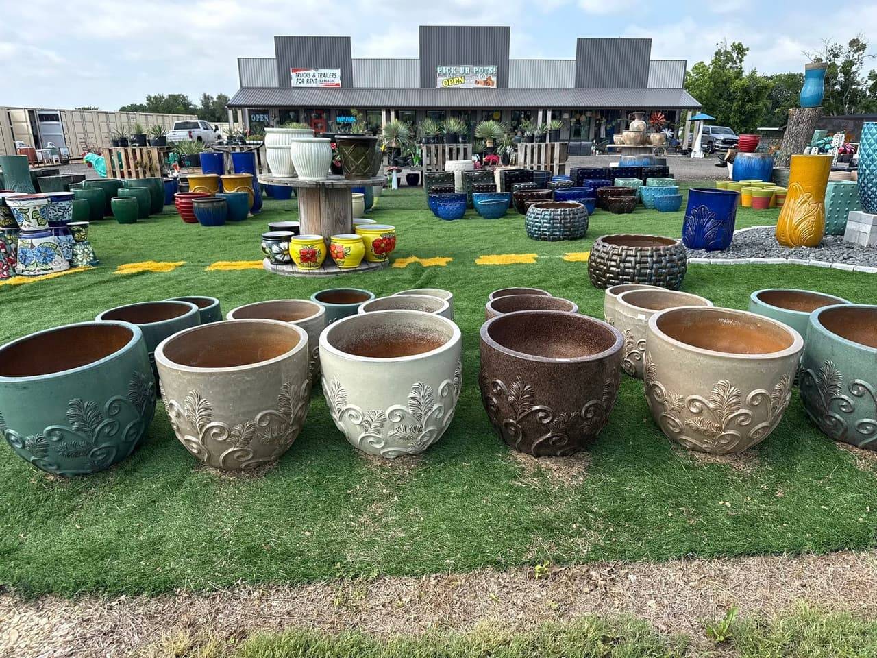 Large glazed planters in teal, cream and brown with leaf and scroll relief in front of the Pick Ur Pots store