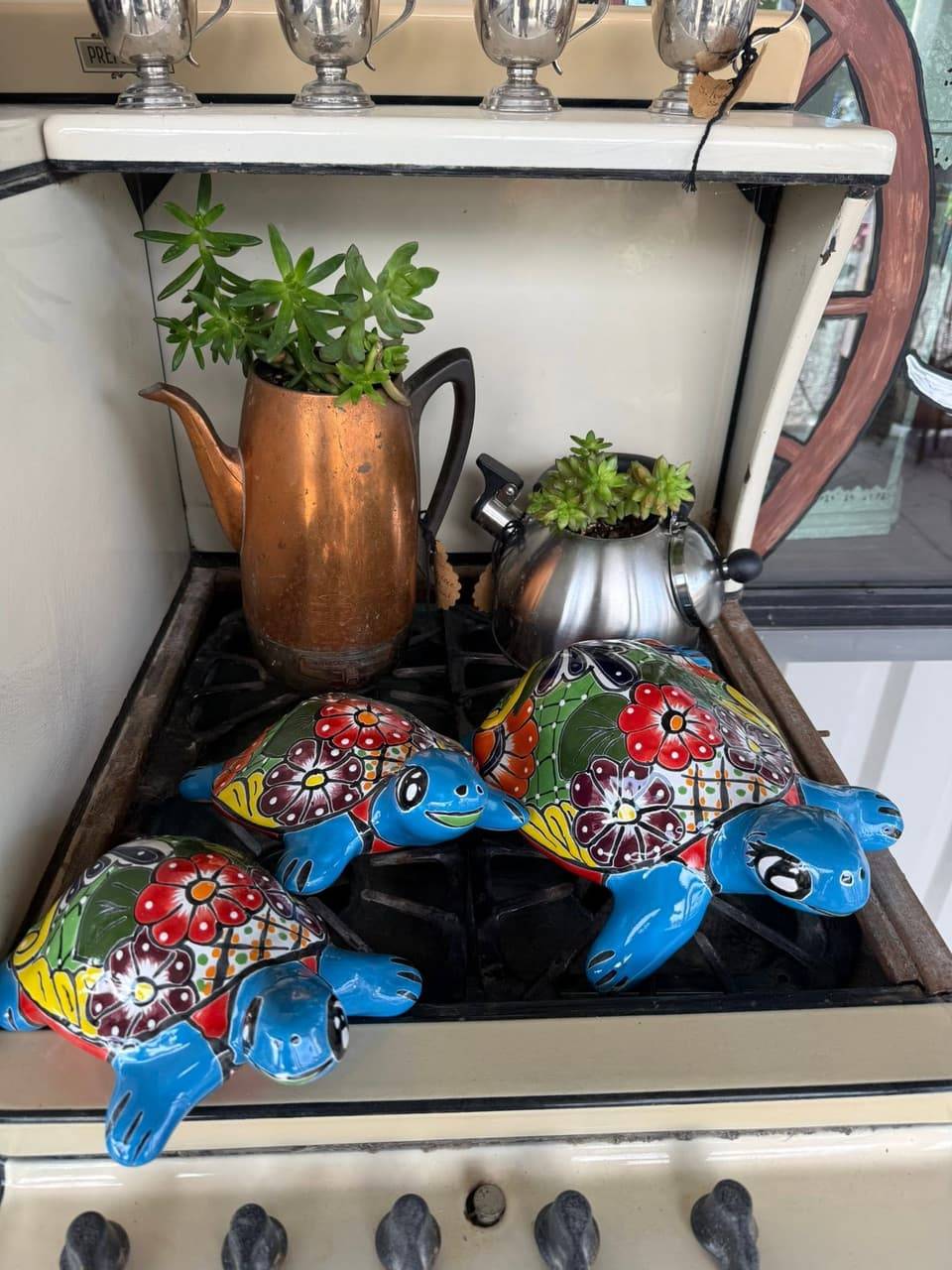 Hand-painted Talavera-style turtle figures on a vintage stove with succulents planted in a copper pot and a kettle