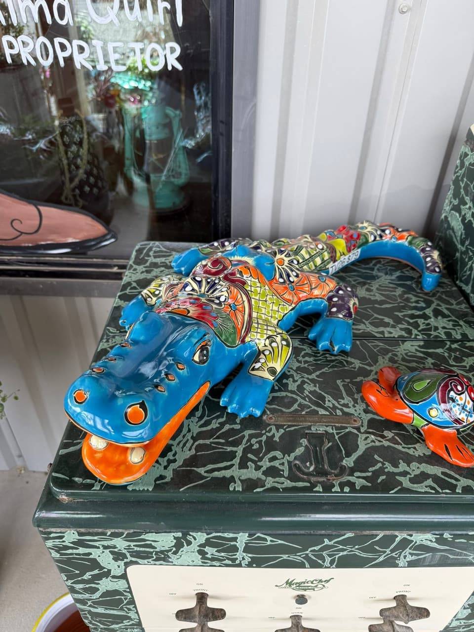 Hand-painted Talavera-style alligator and turtle figures on a vintage green stove