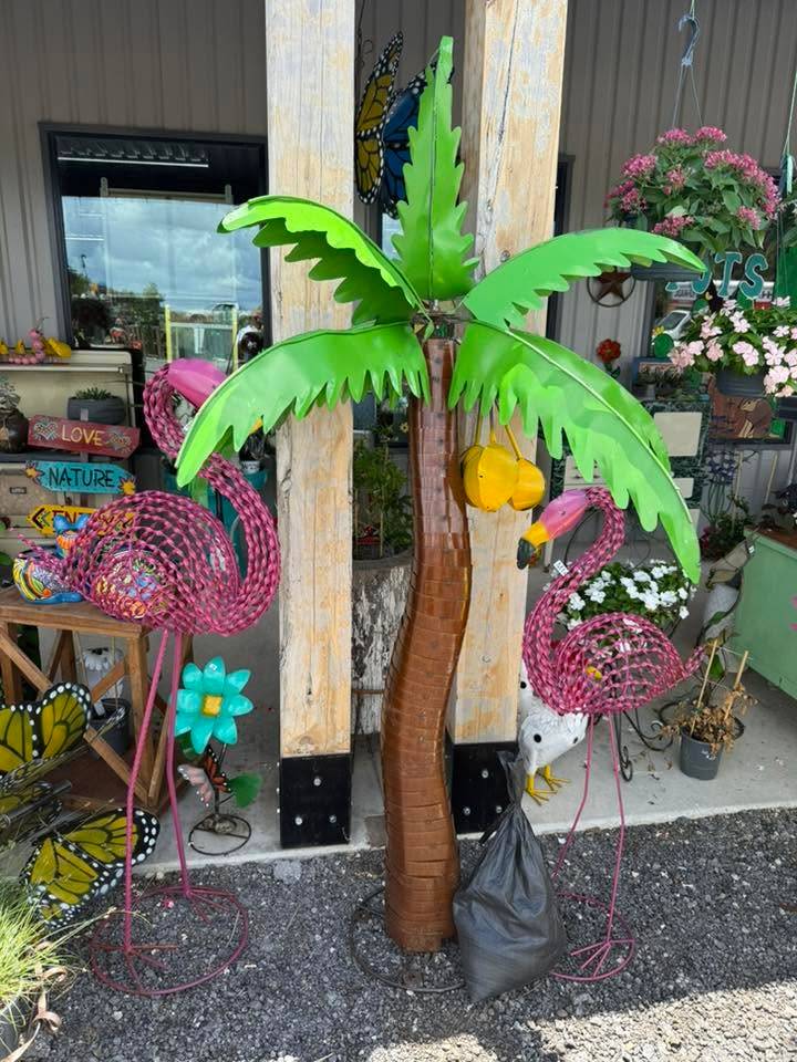 Pink metal flamingos and a green metal palm tree yard art on the porch at Pick Ur Pots
