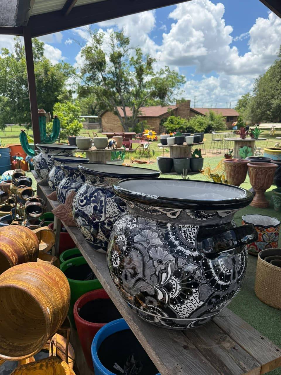 Row of large black and white hand-painted Talavera-style planters on a wooden bench