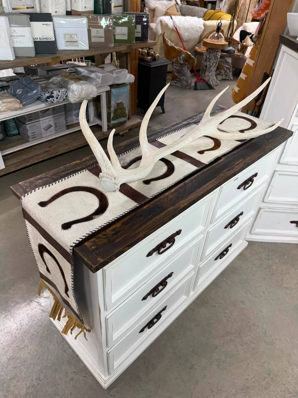 White painted dresser with a dark wood top, a horseshoe cowhide table runner and a shed antler
